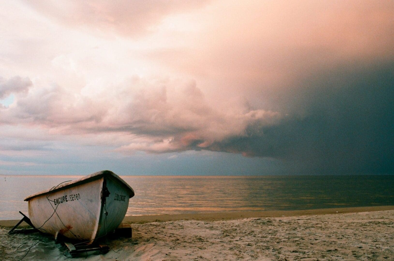 A boat on the beach under a cloudy sky.